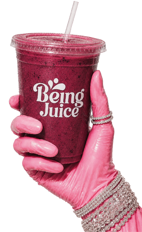 A hand holding a Being Juice berry smoothie